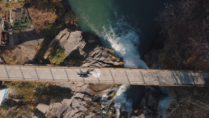 Newlyweds. Bride and groom lie on a bridge over a mountain river. Aerial view