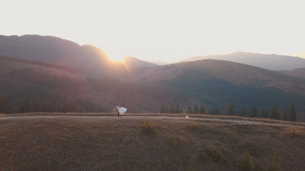 Newlyweds dancing on a high slope of the mountain. Groom and bride. Aerial view