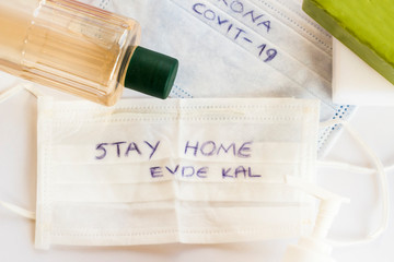 Traditional Turkish Cologne bottle,soaps and disinfectant around of medical face masks with "stay home,evde kal"writing on it,in English and Turkish.
