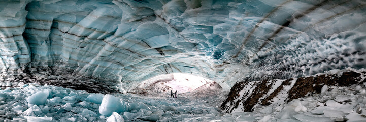 Historic ice cave located outside of Haines Junction in Kluane National Park, Yukon Territory with a couple, two people holding hands in love, romantic panoramic view. 