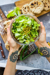 Woman holds green herbal leaves fresh detox salad in glass bowl in hands. Vegan, vegetarian healthy diet food