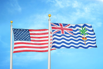 United States and British Indian Territory two flags on flagpoles and blue cloudy sky