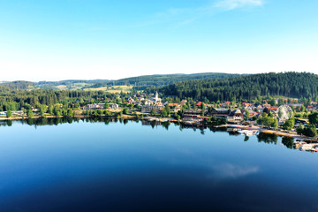 Fototapeta na wymiar Small town of Lake Titisee near the Black Forest of Germany in summer; blue and calm lake, green hills