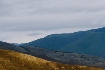 mountain valley under cloudy sky, rock ridge on horizon, hiking in  mountains, rest and meditation in nature