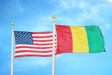 United States and Guinea two flags on flagpoles and blue cloudy sky