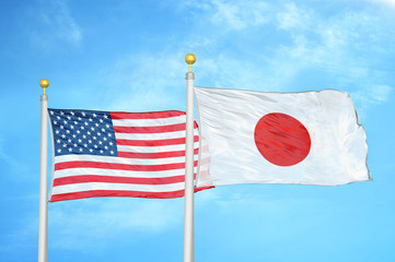 United States and Japan two flags on flagpoles and blue cloudy sky