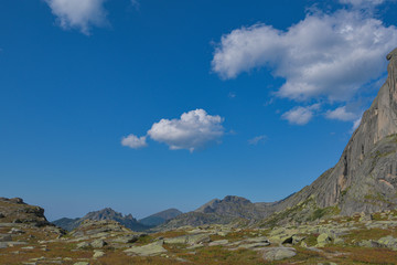 peak under blue sky with clouds, preparation for climbing rock ridge, journey in mountain valley