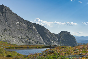 lake under rock ridge, autumn hiking in mountain valley