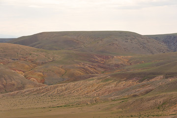 Fototapeta na wymiar gentle red hills, journey through mountain valley, pastures for animals, soil erosion in arid steppe
