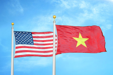 United States and Vietnam two flags on flagpoles and blue cloudy sky