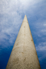 long concrete electric pole against the blue sky, close-up