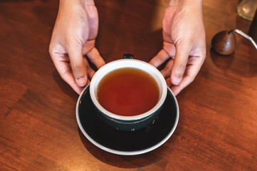 Close up of hands barista man serving coffee in coffee shop. male hands placing a cup of coffee on table. Coffee, Barista, extraction, serve, cafe, lifestyle concept.