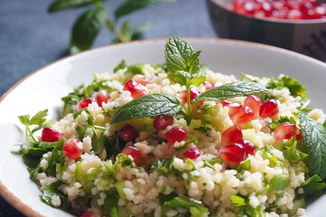 Healthy salad with couscous, fresh mint, cucumber, pomegranate, lemon and olive oil. Eastern cuisine. Vegan food concept. Traditional Israeli food