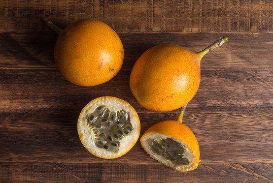 Sweet granadilla or grenadia passion fruit. Whole and cut in half exotic fruits on wooden board