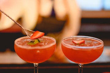 The young bartender is making a cocktail and decorating it in a martini cocktail glass for beautiful at a nightclub bar. Vodka, cocktail, alcohol, beverage, restaurant, relax concept.