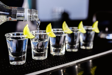 Gin or vodka with lime. Many glass with a cocktail alcohol with lemons on the black blue surface....