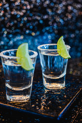 Gin or vodka with lime. Two glasses with a cocktail alcohol with lemons on the black blue surface. Vodka, cocktail, alcohol, beverage, restaurant, relax concept.
