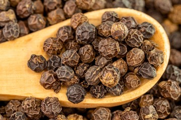 Peppercorns on a wooden spoon close up