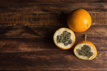 Sweet granadilla or grenadia passion fruit. Whole and cut in half exotic fruits on wooden board....