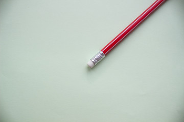 One red pencil on a light green background.