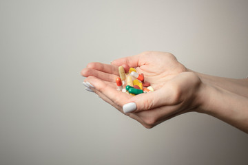 A handful of various pills in a woman's hands. Medications against the COVID-19 and other conditions and diseases on the grey background. Medicine.