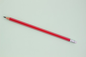 One red pencil on a light green background.