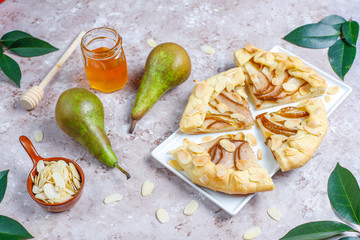 Homemade pear galette pie with almond leaves and fresh ripe green pears