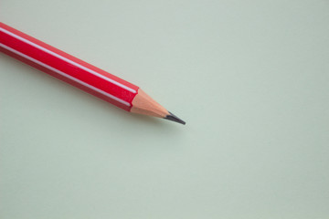 One red pencil on a light green background.