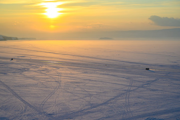 View of frozen lake Baikal in winter season at sunset. The surface of lake covered by snow. Lake Baikal is the world's deepest lake located in southern Siberia, Russia.