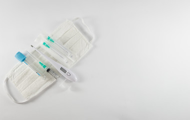 Diverse medical equipment isolated on white background. Surgical protection face mask, syringe, needles, test tube and digital thermometer. Corona Covid-19 protection concept, top view, copy space.