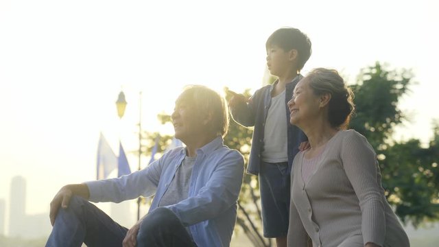 asian grandmother grandfather and grandchild relaxing outdoors in park