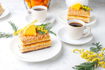Orange cake decorated with fresh orange slices and mimosa flowers on light background