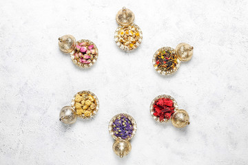 Assortment of dry tea in golden vintage mini plates.Tea types background:hibiscus,chamomile,mixed black tea,dry roses,butterfly pea tea