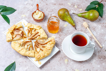 Homemade pear galette pie with almond leaves and fresh ripe green pears