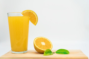 ORANGE  ON A WOODEN BOARD, TOGETHER WITH A JUICE OF ORANGE AND DECORATED WITH GREEN LEAVES AND A JUICE OF ORANGE. FRONT VIEW