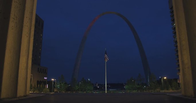 Wide shot of saint louis arch and american flag with slow zoom at night