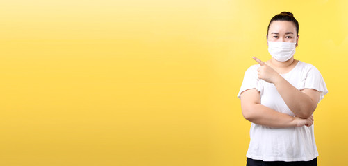 Asian woman using alcohol gel and wearing medical mask,Recommend the prevention of viruses and various diseases. isolated on yellow background in studio With copy space.