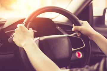 Female hands on the steering wheel of a car while driving. Against the background, the windshield...