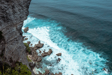 The beautiful nature of Indonesia and the island of Bali. Slopes and cliffs overlooking the waves of the blue ocean. Tropical and exotic view of travel to Asia