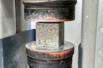 Concrete cube is installed in a testing machine to conduct a compressive strength test.