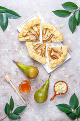 Homemade pear galette pie with almond leaves and fresh ripe green pears