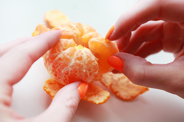 female hand with bright manicure holds a mandarin