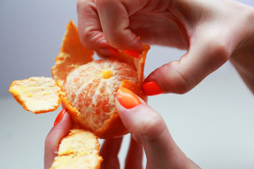 female hand with bright manicure holds a mandarin