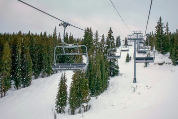 Ski lift at resort in Vail Colorado surrounded by green trees - obrazy, fototapety, plakaty