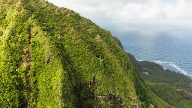 Aerial shot of coastal highlands.View of a huge long ridge extending into the distance. Massif is densely covered with tropical greenery. Ocean is seen behind. Exotic travel location. Hawaii. 4K