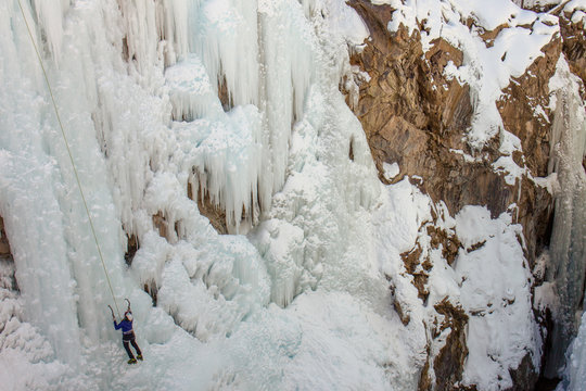 Ouray, Colorado / USA - 26 January 2020: Female ice climber scaling a massive wall of ice