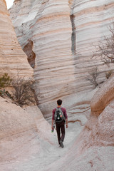 Young man with backpack walks in a desert southwestern canyon in New Mexico