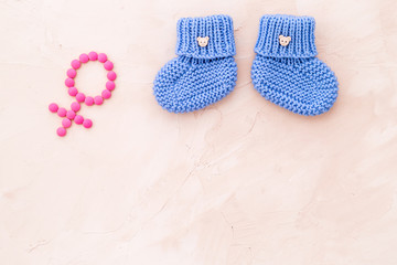 Baby booties for girl - pregnancy concept with Venus sign - on beige background top-down copy space
