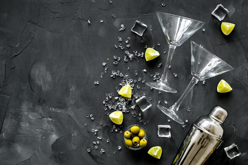Bar background with martini glasses, shaker, ice, lemon and olives on grey table top-down copy space