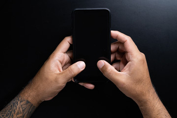 Mobile phone in hand on black background.